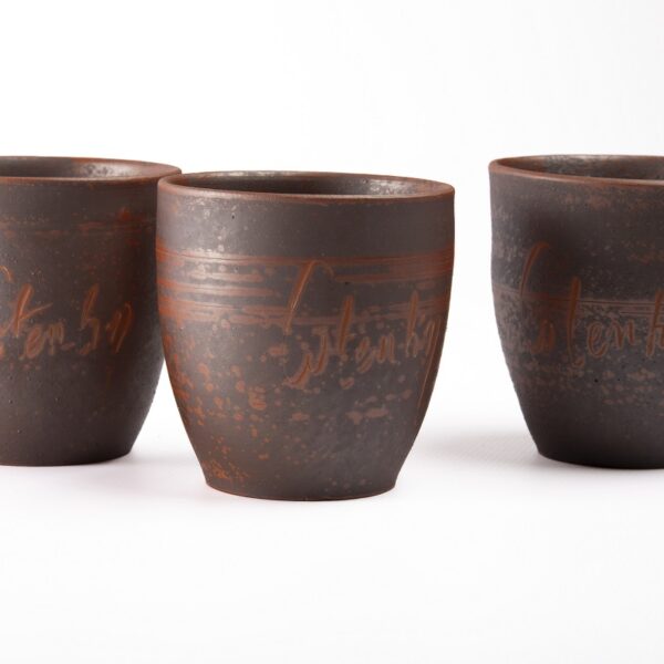 Trois mugs en céramique artisanale portant chacun le nom Cotentin écrit à la main en lettres irrégulières,
